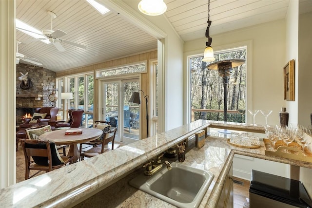 kitchen with pendant lighting, a healthy amount of sunlight, light stone countertops, and sink