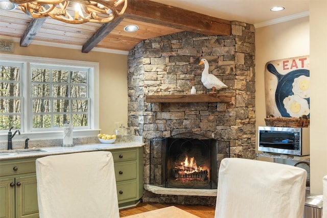 sitting room featuring a fireplace, sink, beam ceiling, and light wood-type flooring