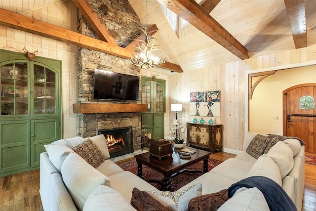 living room featuring wooden walls, wood-type flooring, a fireplace, and lofted ceiling with beams