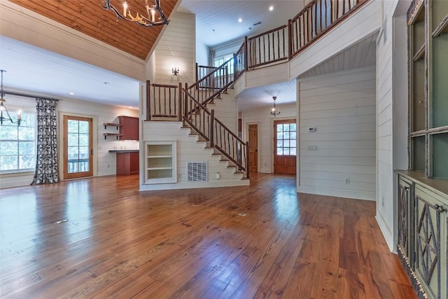 96 Mahalo Ln, Cullowhee, NC 28723 - unfurnished living room with a chandelier, a high ceiling, stairway, hardwood / wood-style floors, and wooden walls