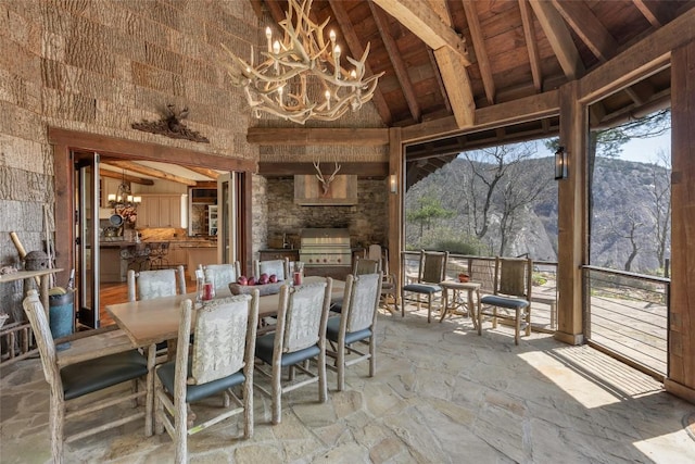 interior space featuring stone flooring, an inviting chandelier, high vaulted ceiling, beamed ceiling, and a mountain view