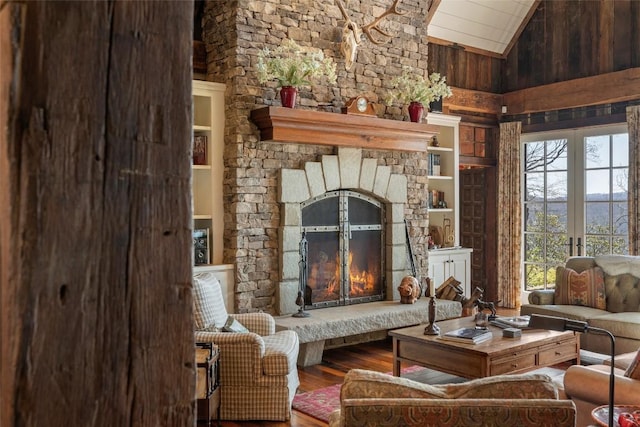 sitting room featuring wooden ceiling, high vaulted ceiling, wood-type flooring, and a stone fireplace