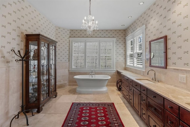 bathroom with a freestanding tub, tile walls, vanity, and a notable chandelier