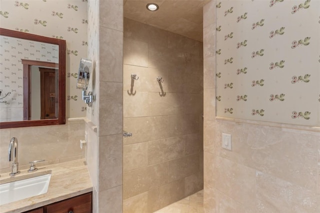 full bathroom featuring a walk in shower, vanity, wallpapered walls, and tile walls