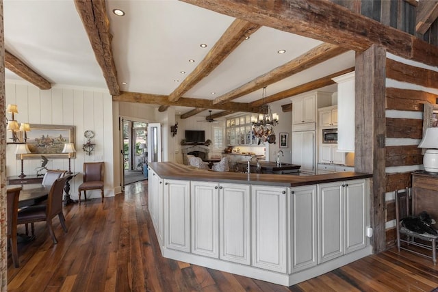 kitchen with built in appliances, recessed lighting, beamed ceiling, and dark wood finished floors