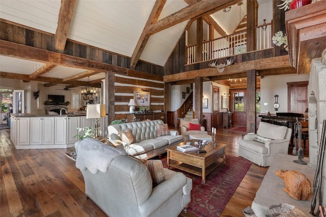 living area with a notable chandelier, wood walls, beam ceiling, and hardwood / wood-style floors
