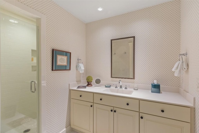 full bathroom featuring vanity, a shower stall, and wallpapered walls