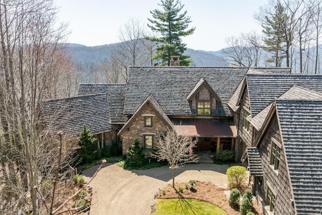 view of front of home with a mountain view, a chimney, and stone siding