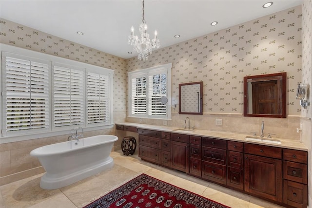 full bath featuring a sink, a freestanding tub, double vanity, and a notable chandelier