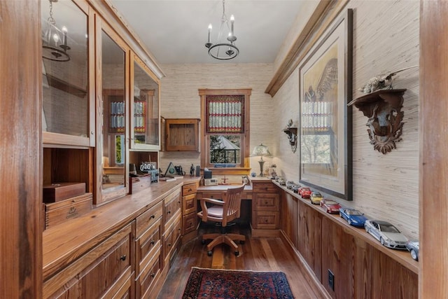 office area featuring a notable chandelier, wallpapered walls, dark wood finished floors, and built in desk