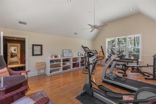 workout area featuring ceiling fan, visible vents, vaulted ceiling, light wood-type flooring, and baseboards