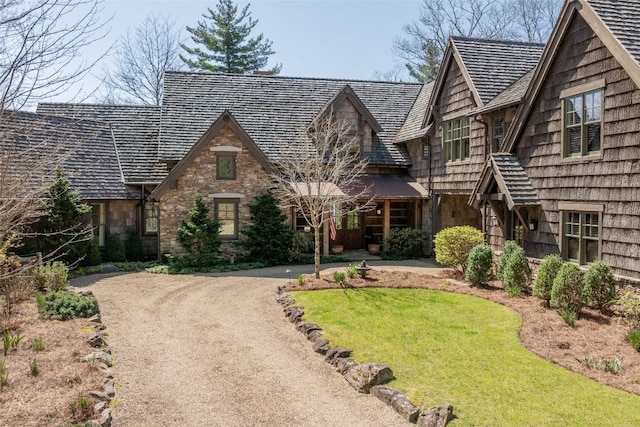 tudor home featuring stone siding, driveway, and a front yard