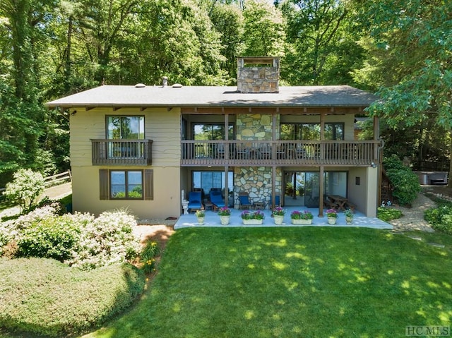 rear view of property featuring a patio area, a lawn, and a chimney