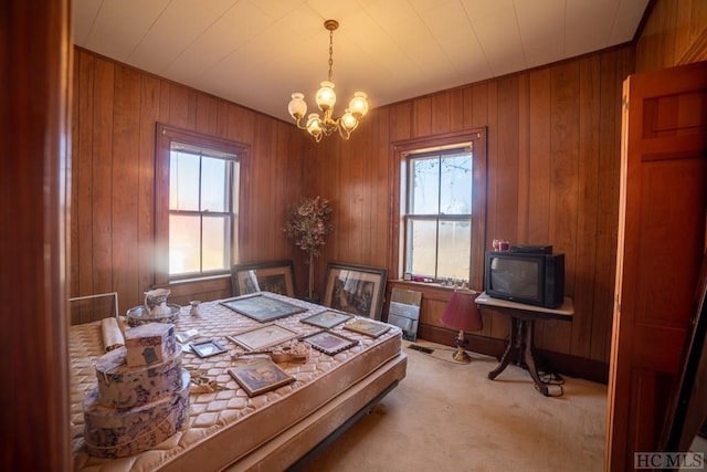 bedroom with a chandelier, light carpet, and wood walls