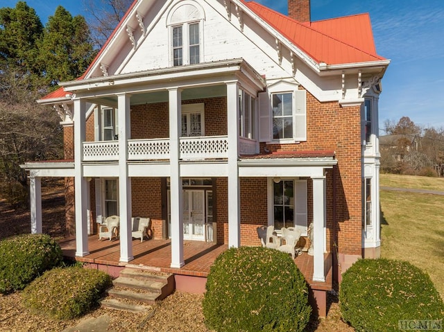 back of property with a balcony and a porch