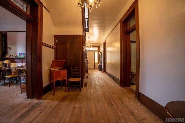 corridor featuring an inviting chandelier and light hardwood / wood-style flooring