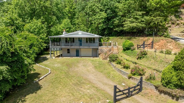 228 Mountain Laurel Dr, Franklin, NC 28734 - rear view of house featuring a wooden deck, dirt driveway, stairs, an attached garage, and a chimney