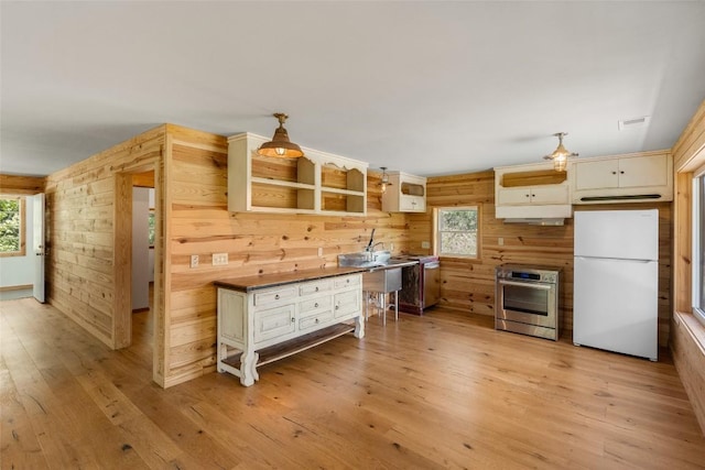 228 Mountain Laurel Dr, Franklin, NC 28734 - kitchen featuring freestanding refrigerator, wooden walls, light wood finished floors, range, and oven