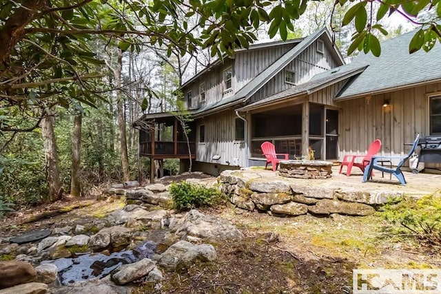 920 Sapphire Post Office Rd, Cashiers, NC 28774 - view of front of house featuring a sunroom, an outdoor fire pit, board and batten siding, a patio area, and roof with shingles