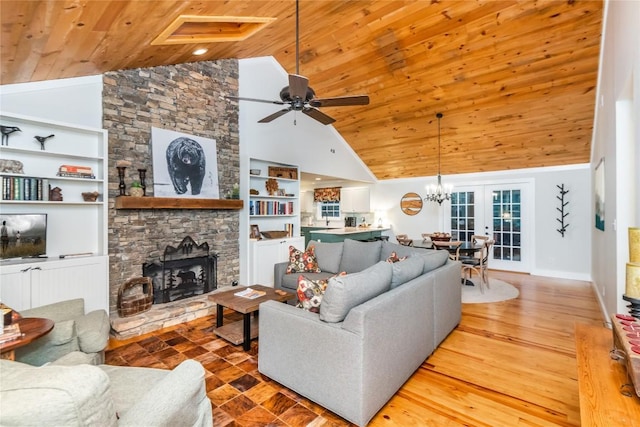 living room featuring built in shelves, a stone fireplace, wood ceiling, wood-type flooring, and ceiling fan with notable chandelier