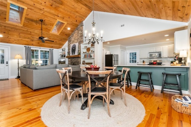 dining space featuring wood ceiling, a skylight, high vaulted ceiling, and light hardwood / wood-style flooring