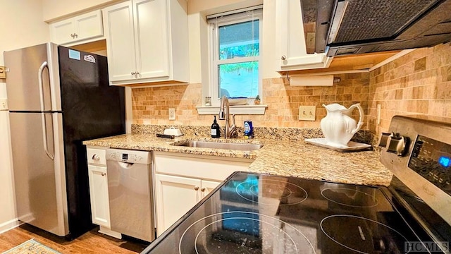 kitchen with sink, light stone counters, light hardwood / wood-style flooring, appliances with stainless steel finishes, and white cabinets