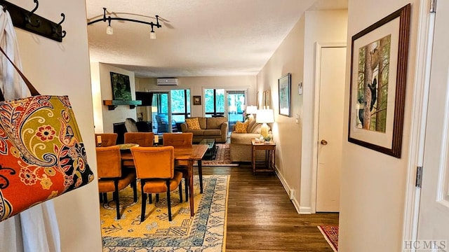 dining room with an AC wall unit, dark wood-type flooring, and a textured ceiling