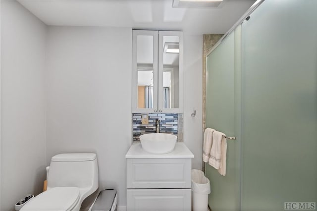 bathroom with tasteful backsplash, vanity, toilet, and a shower with shower door