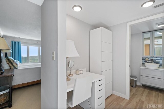 interior space featuring hardwood / wood-style flooring, vanity, and decorative backsplash