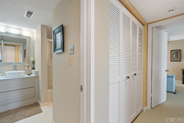 hallway featuring sink, light tile patterned floors, and a textured ceiling