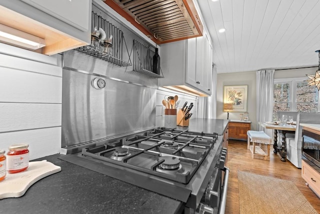 kitchen featuring wood ceiling, stovetop, range hood, light wood-style flooring, and white cabinetry