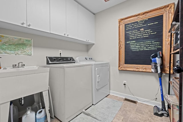 washroom with visible vents, baseboards, cabinet space, a sink, and washing machine and dryer