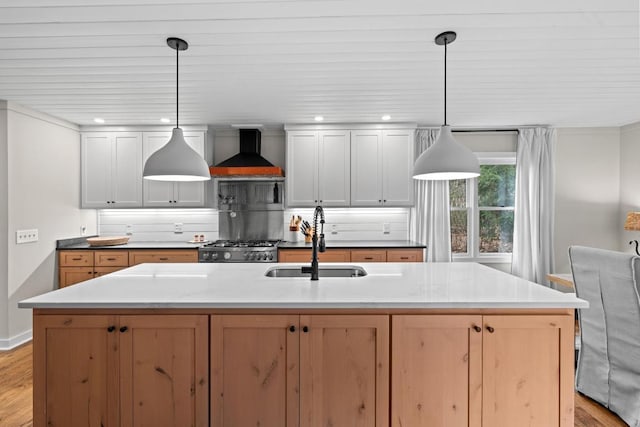 kitchen featuring light wood-type flooring, a sink, wall chimney range hood, decorative backsplash, and stove