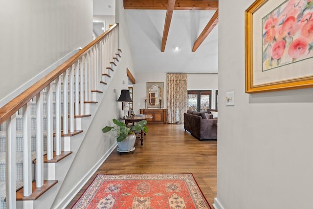 hallway with beam ceiling, high vaulted ceiling, wood finished floors, stairway, and baseboards