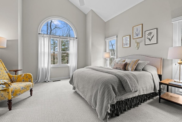 bedroom featuring multiple windows, light colored carpet, baseboards, and high vaulted ceiling