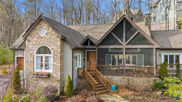 english style home featuring a shingled roof, a sunroom, and a chimney