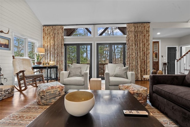 living room with wood finished floors, stairway, french doors, and a healthy amount of sunlight