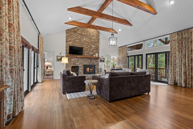 living room featuring a stone fireplace, wood finished floors, french doors, and beam ceiling