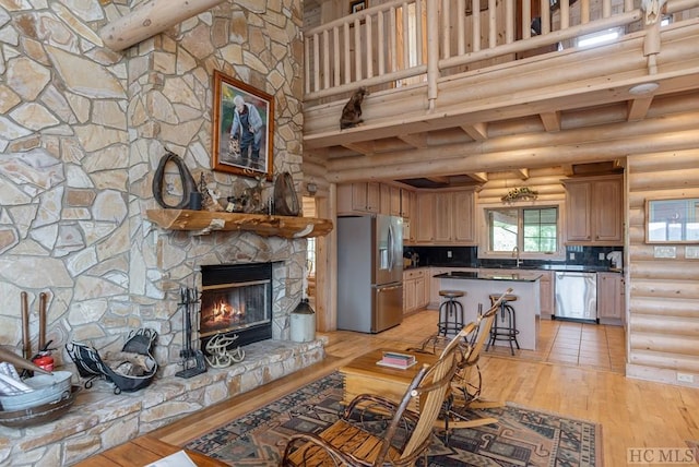 living room with a stone fireplace, light hardwood / wood-style floors, rustic walls, and a high ceiling