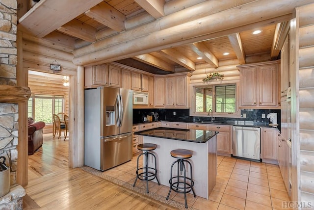 kitchen with light brown cabinetry, wood ceiling, appliances with stainless steel finishes, a kitchen island, and log walls