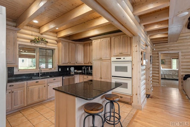 kitchen with sink, log walls, white double oven, and a center island