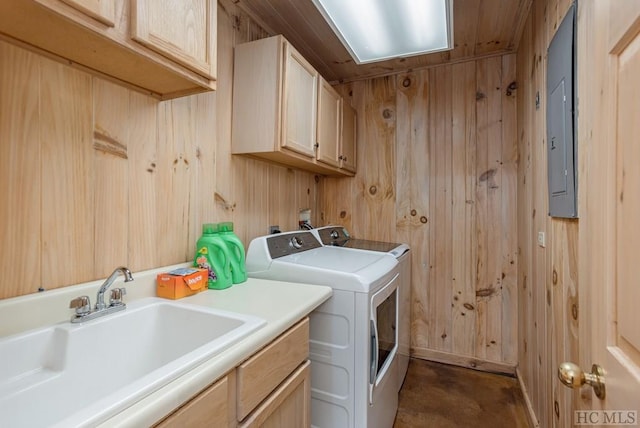 laundry area with wood walls, separate washer and dryer, sink, cabinets, and electric panel