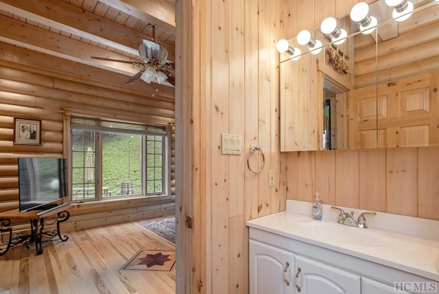 bathroom with rustic walls, hardwood / wood-style flooring, vanity, wooden ceiling, and beam ceiling