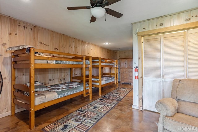 bedroom with ceiling fan and wooden walls