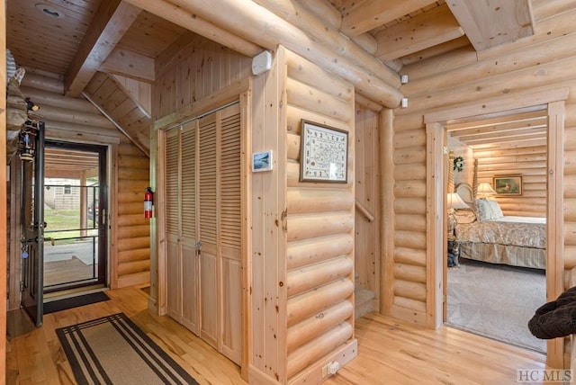 hallway featuring beam ceiling, rustic walls, light hardwood / wood-style floors, and wood ceiling