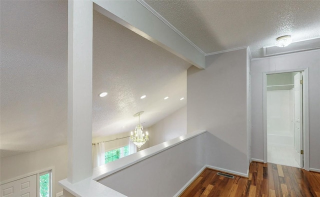 hall featuring a wealth of natural light, visible vents, a textured ceiling, and wood finished floors