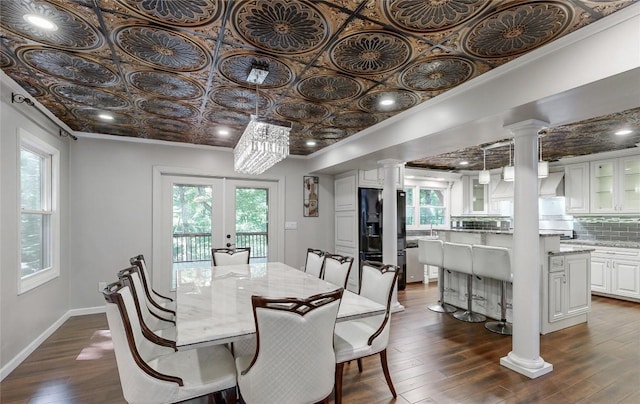 dining area featuring ornate columns, dark wood finished floors, an ornate ceiling, and a wealth of natural light