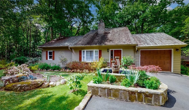 single story home with a chimney, aphalt driveway, and a garage