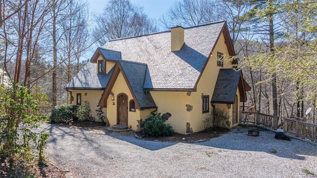 view of front facade with a chimney, a high end roof, and stucco siding