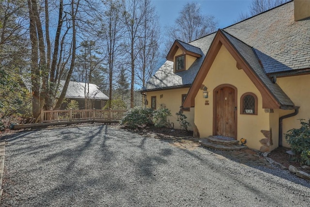 view of front of home with a high end roof, a deck, and stucco siding